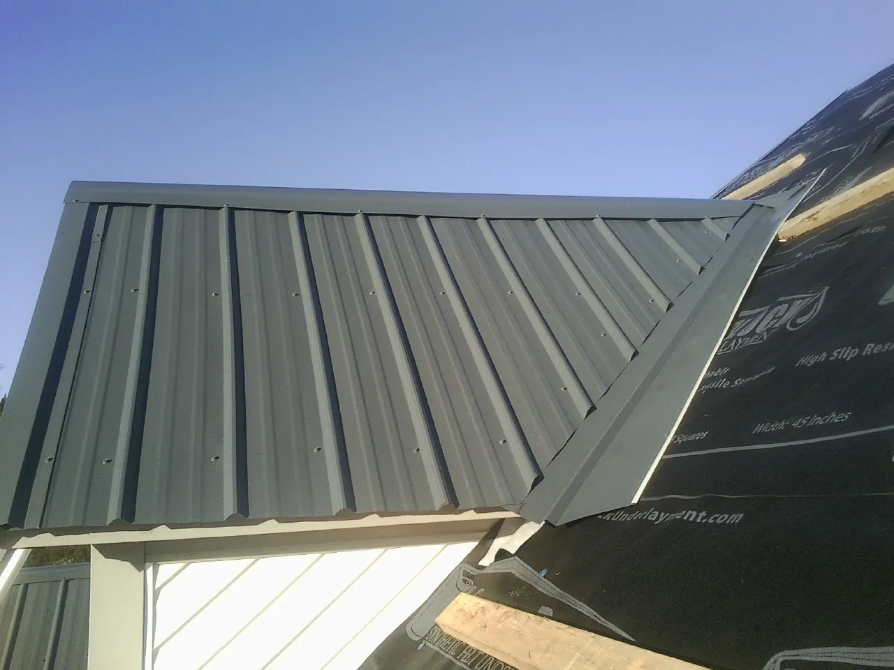 Gray metal roof panels going on over a garage gable in Ruston