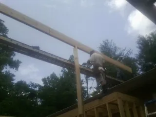 Carpenter setting a ridge beam over a new addition frame — Ice Dam Removal by Roofing Brothers in Ruston