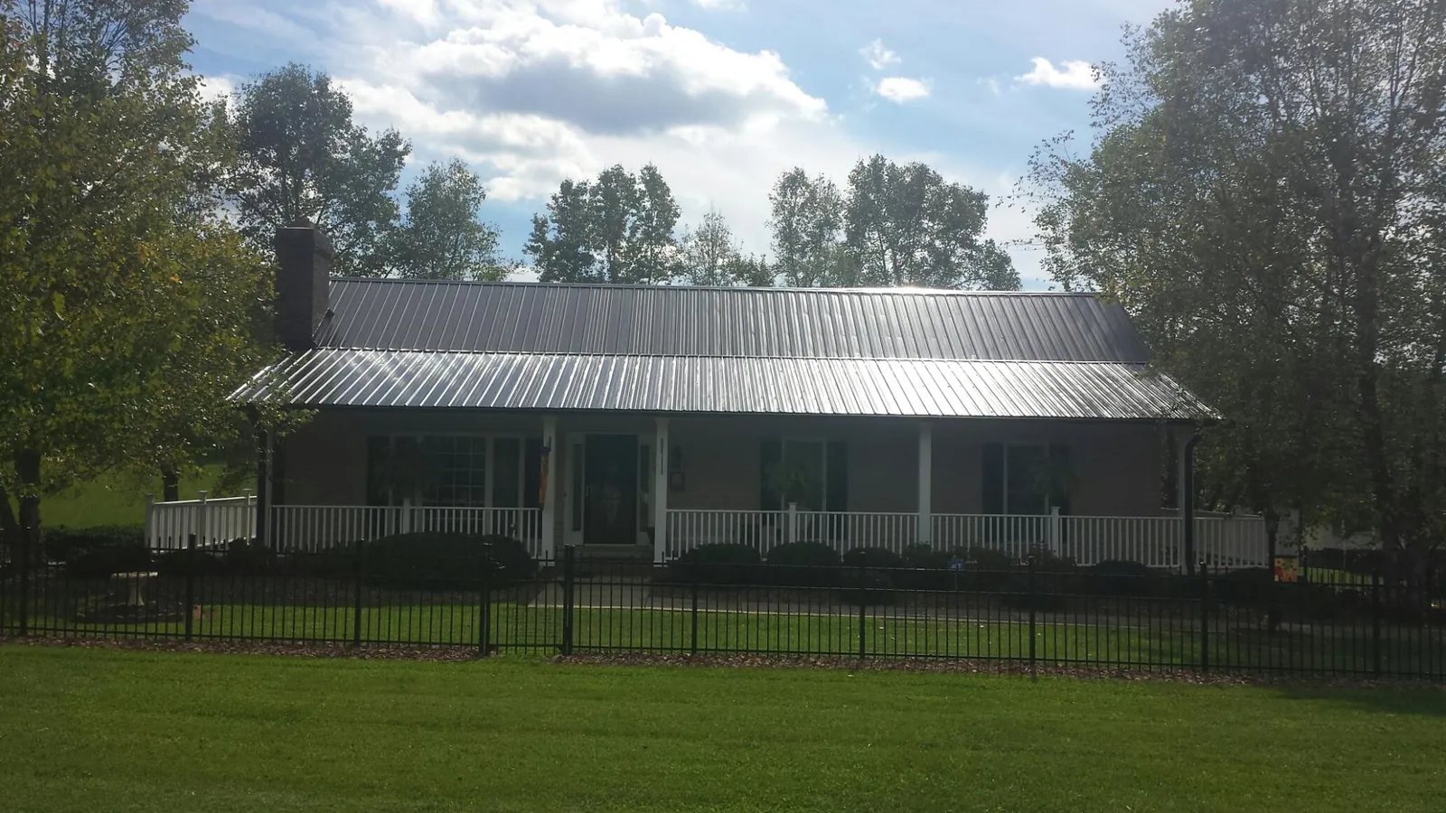 Gray metal roof on a brick ranch with a full width front porch — Gutter Guard Installation work by our crew in Ruston