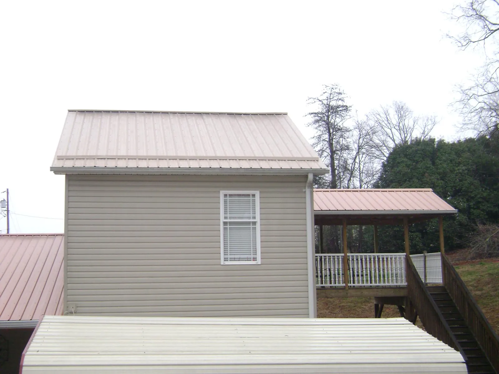 Tan metal roofs on a two story addition and attached porch, from a Roof Replacement job in Ruston