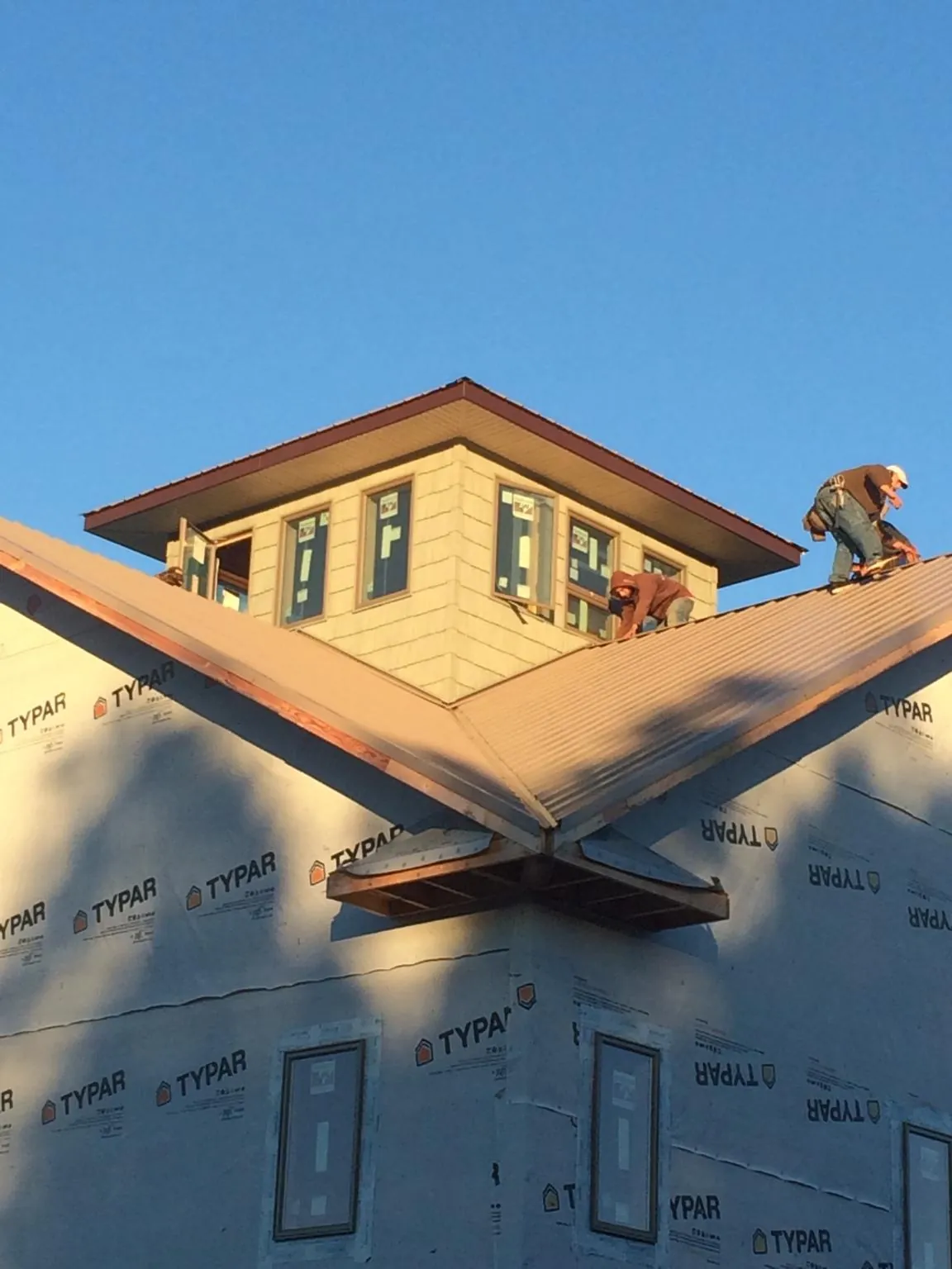 Roofers working around a rooftop cupola on a new metal roof at sunset — Roof Waterproofing in Ruston by Roofing Brothers